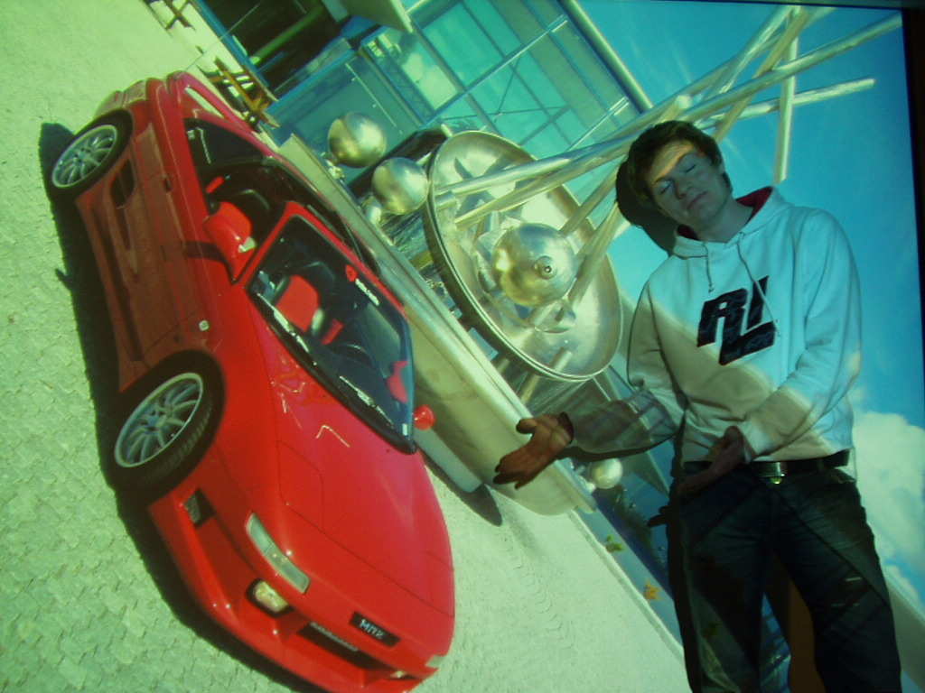 SW20 poserer forran lerretet med bilen sin..