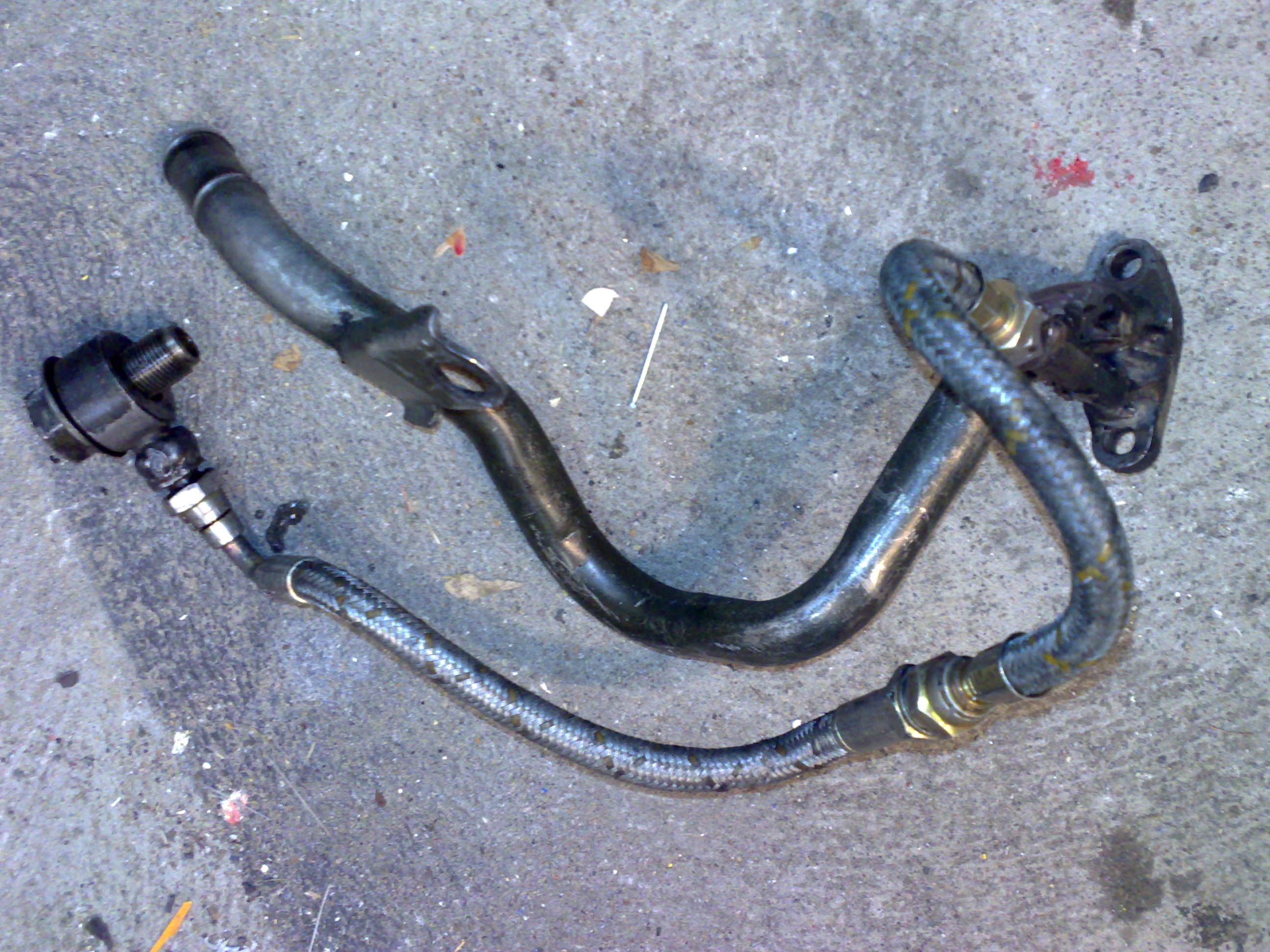 Modifisert. Her ser du hvor det er festet. 1 bolt for oljetilførsel (den du har merket på bildet) og staget med hull i som den er festa på blokka med. Disse to må løsnes for å få den av.